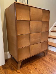 a wooden dresser sitting on top of a hard wood floor next to a stair case