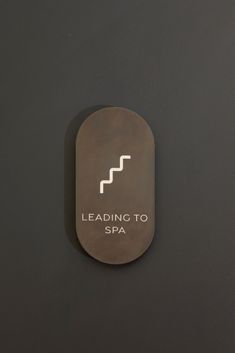 a sign that says leading to spa on the side of a black wall with white lettering