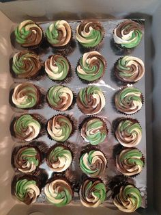 a box filled with green and white cupcakes