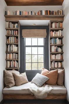 a window seat with bookshelves and pillows on it