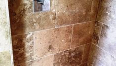 a tiled shower stall in a bathroom with brown and white marble tiles on the walls