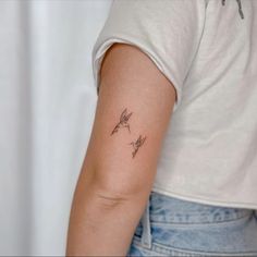 a woman's arm with two small birds on the left side of her arm