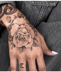 a person's hand with a rose tattoo on it and moon in the background