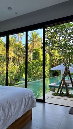 a bed sitting in a bedroom next to a large glass window overlooking a lush green forest