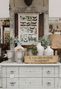 an old dresser with vases and plants on it