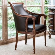 a brown leather chair sitting in front of a window