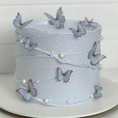 there is a white cake with blue butterflies on the top and pearls around the edges