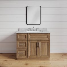 a bathroom vanity with a mirror above it and wooden floors in front of the wall