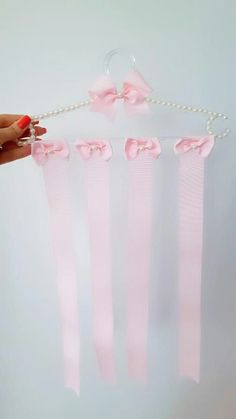 a person holding pink ribbon with bows attached to the string and pearls hanging from it