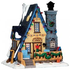 a christmas village with lights and decorations on the top of it's roof, next to a fire hydrant