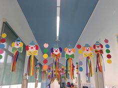 colorful paper clowns hanging from the ceiling in a room with polka dots and rainbow streamers