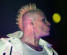 a man with punk hair and piercings on his head is looking off into the distance