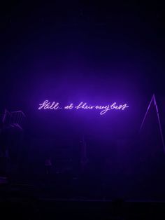 purple neon sign in the dark with people standing around it and one person holding an umbrella