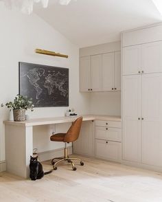 a cat sitting on the floor in front of a desk with a black and white map