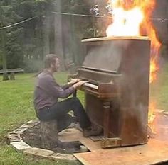 a man sitting on the ground playing a piano in front of a fire hydrant