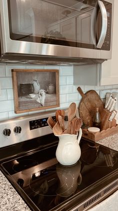 a kitchen with a stove, microwave and utensils on the burner in front of it