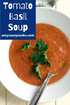 tomato basil soup in a white bowl with a spoon and parsley on the side