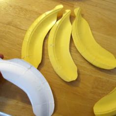 someone is cutting up some banana slices on a wooden table with a pair of scissors