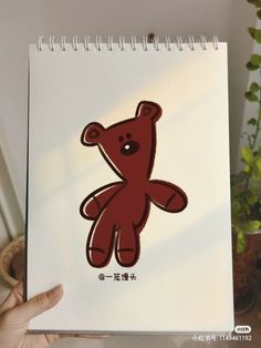 a hand holding up a drawing of a teddy bear with chinese characters on it's back