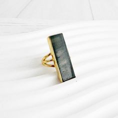 "Large Labradorite Rectangle Bar Statement Ring in Gold and Silver. Crystal Stone Cocktail Ring. Gold Silver Gemstone Ring The definition of a wear-anywhere statement. This ring features a large rectangular stone and a simple band design that add the finishing touch to any look. GEMSTONE: Labradorite STONE SIZE: 1.15\" long RING SIZE: Adjustable MATERIAL: Gold/Silver plated brass Find more unique statement rings here - https://www.etsy.com/shop/RusticGem?section_id=45302653 Questions?  Please don't hesitate to start a convo, we'd love to hear from you! WELCOME! Welcome to Rustic Gem Jewelry! Thank you for visiting our shop. We take custom orders and can often do a similar piece in different colors. We also offer bulk / bridal discounts. If you have any questions regarding this item, please Ring Rectangle, Long Ring, Simple Band, Band Design, Gold Cocktail Ring, Gem Ring, Statement Ring Silver, Labradorite Ring, Labradorite Stone