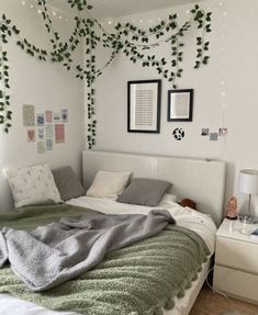 an unmade bed in a white bedroom with ivy growing on the wall above it