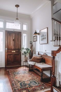 a living room filled with furniture next to a wooden stair case and a rug on top of a hard wood floor