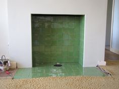 a green tile fireplace in a room with no one around it or the fire place