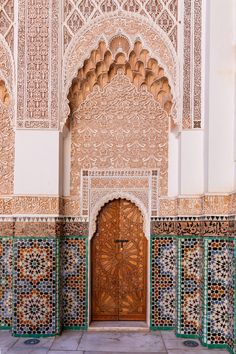 an ornate doorway in the middle of a building with tile work on it and wooden doors