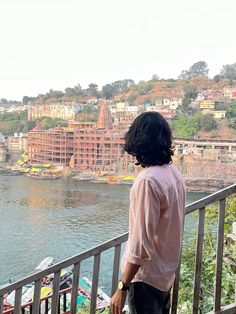 a man standing on top of a balcony next to a river