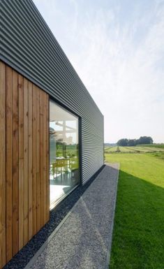 a wooden building sitting on top of a grass covered field next to a lush green field