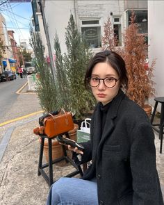 a woman sitting on a chair with a suitcase in her lap and looking at the camera