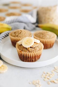 three banana muffins on a white plate next to some oatmeal