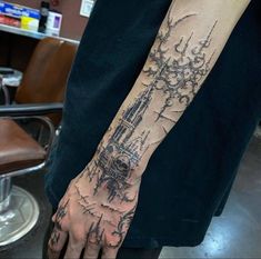 a man's arm with a castle tattoo on the left side of his hand