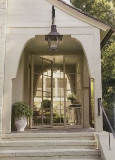 an entry way with steps leading up to the front door and potted plants on either side