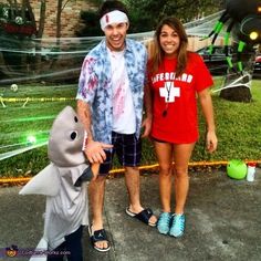 a man and woman standing next to each other in front of a fake shark costume