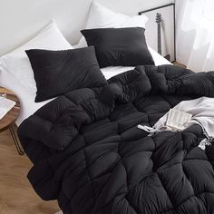 a bed with black comforter and pillows on it