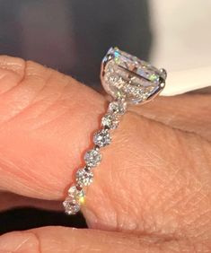 a close up of a person's hand with a diamond ring on their finger