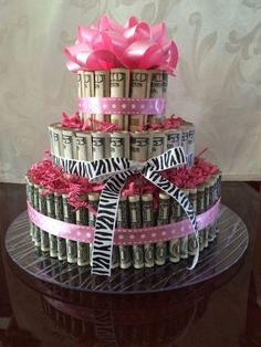 a three tiered cake made out of stacks of money with pink ribbon and bow