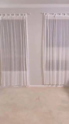 an empty room with curtains and a bed