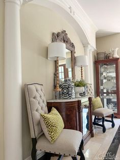 a living room filled with furniture and a mirror on top of a wall next to a doorway