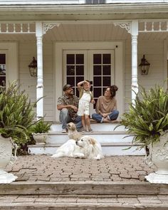 three people and a dog sitting on the front steps of a house