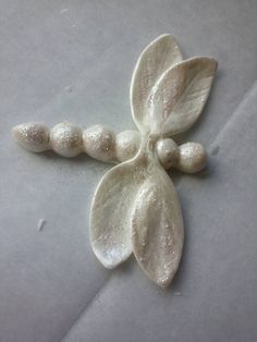 a white flower with three petals on it's side, sitting on top of a piece of paper