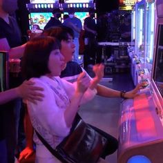 two people standing next to each other in front of a vending machine