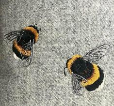 two yellow and black bees sitting on top of a gray sweater