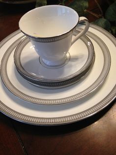 a white cup and saucer sitting on top of a plate with silver trimmings