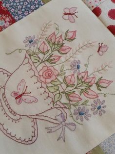 a close up of a piece of cloth with flowers on it and butterflies in the background