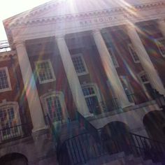 the sun shines brightly in front of an old building with columns and pillars on it