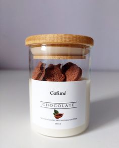 a jar filled with chocolate cookies sitting on top of a white table next to a wooden lid