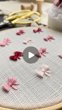 the video is showing how to make an embroidered flower design on fabric with scissors and thread