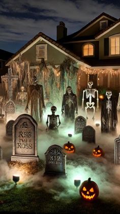 a house decorated for halloween with pumpkins and ghost statues in the front yard at night